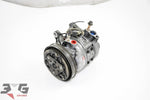 OEM factory AC compressor unit for Nissan Skyline R33 with RB20E engine, showing the front view with piping and connectors.